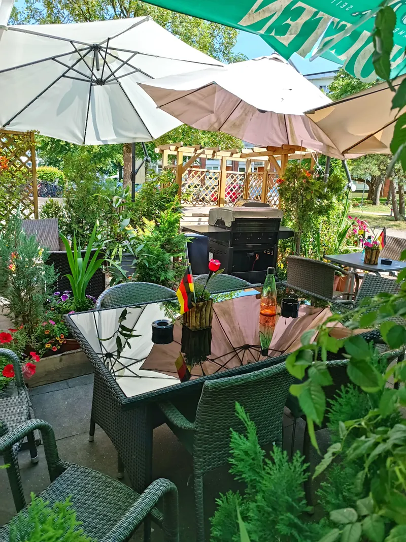 Bepflanzte Terrasse mit Tischen und Sonnenschirm